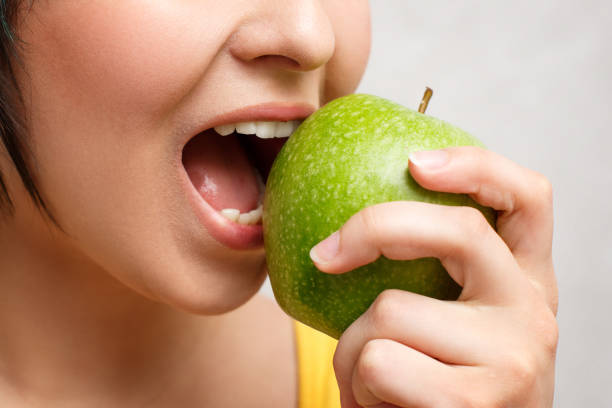 istock girl eating a green Apple. close-up, grey background 1241003328