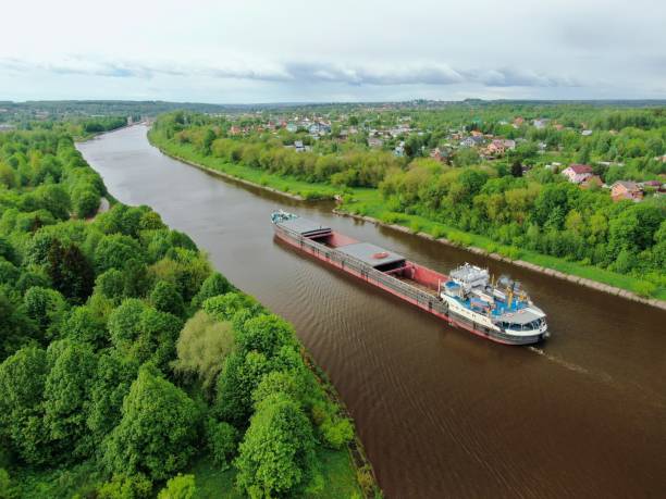 istock Flying over a large cargo ship with open holds sailing down a calm river surrounded by forest. Carriage of goods by river. Beautiful panoramic landscape. Top view down 1241021058