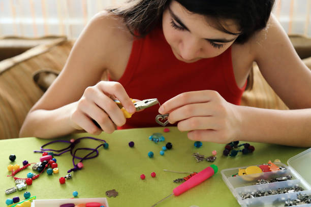 Young girl making bead bracelets Young girl making bead bracelets at home bead photos stock pictures, royalty-free photos & images