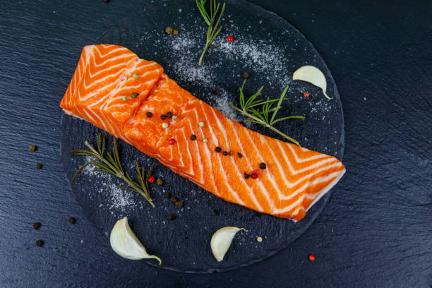 istock Raw salmon fillet with spices on black slate. Top view 1241042458
