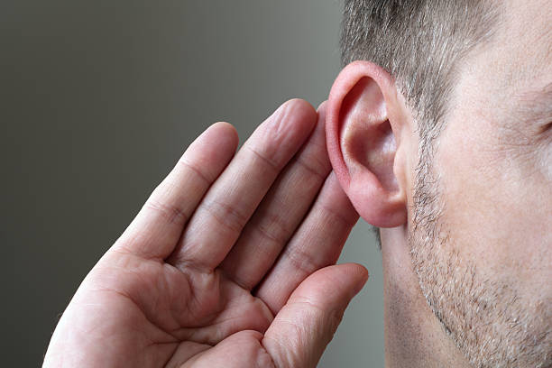 Listening Close up on hand and ear listening for a quiet sound or paying attention human ear stock pictures, royalty-free photos & images