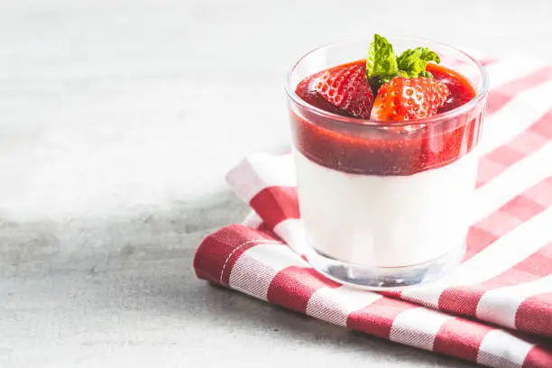 Italian dessert panna cotta with strawberries on checkered napkin.