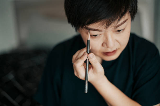 istock an asian chinese mid adult is getting ready doing makeup before leaving her apartment to work drawing her eyebrow 1241094774