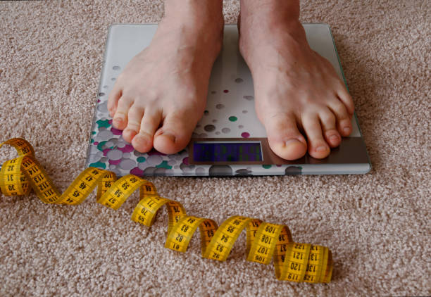 istock man is weighed on an electronic scale. next to which is a measuring tape. 1241095191