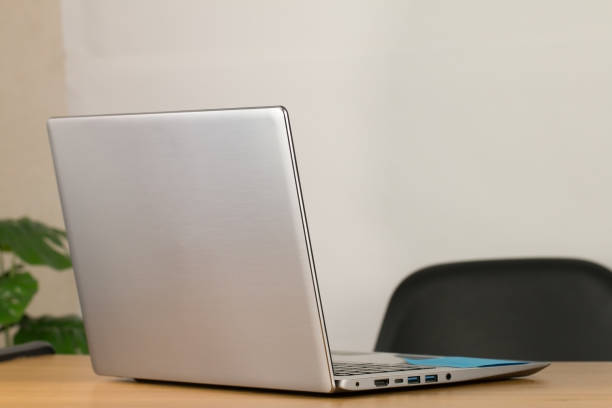 istock Grey notebook computer Leave it ready for work. Resting on a brown wooden office desk And there is a black chair White wall background The picture on the right is decorated with green trees. 1241098692