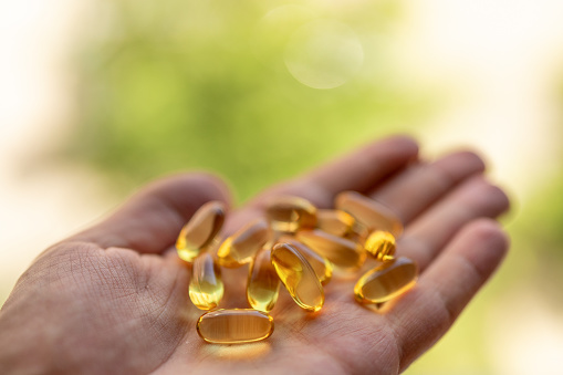 A handful of vitamin d capsules is in a man's hand.