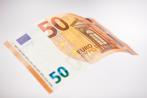 High resolution photograph of a bent 50 Euro bill (new version since 2017), shalow depth of field.