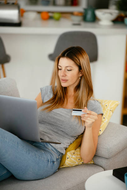 istock Young woman using her credit card and laptop at home. 1241127430