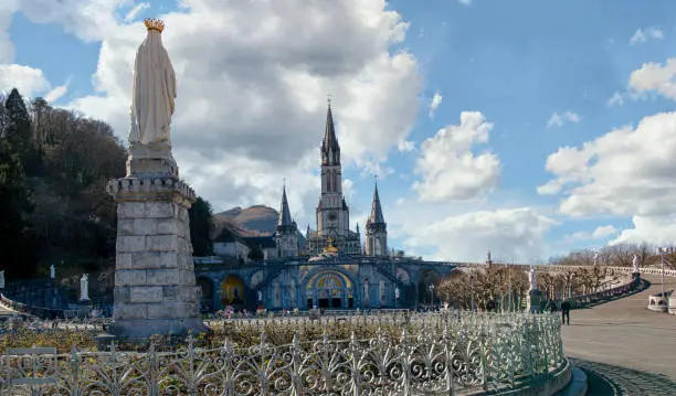 Photo of Virgin of Lourdes on the blue sky with clouds, France