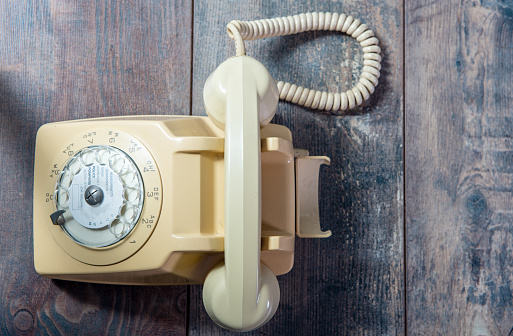beige old telephone on the wooden background