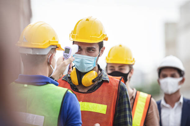 Officer checking fever team engineer and technician foreman with digital thermometer in cargo container shipping. Prevent the outbreak of the virus covid-19. Officer checking fever team engineer and technician foreman with digital thermometer in cargo container shipping. Prevent the outbreak of the virus covid-19. covid thermometer stock pictures, royalty-free photos & images