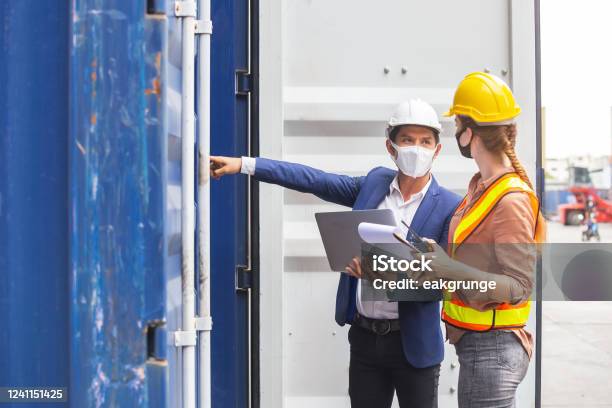 Teamwork Foreman Man And Woman Wearing Protection Face Mask And Safety Helmet Using Laptop And Holding Clipboard Checking Containers In Cargo Ship For Import Export Industrial Container Cargo Concept Stock Photo - Download Image Now