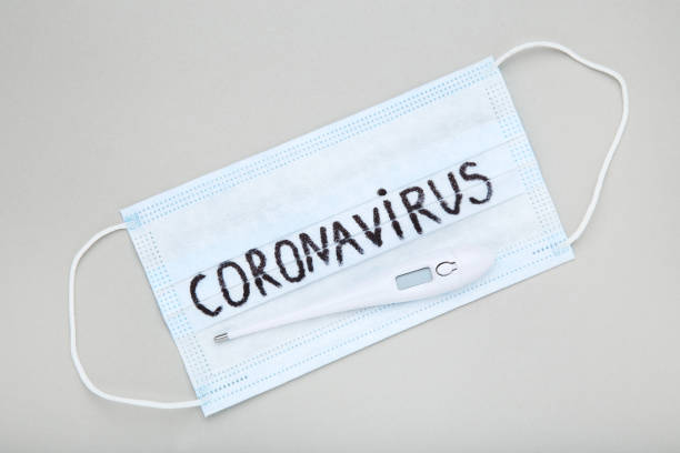 istock Mask with text Coronavirus and thermometer on gray background 1241162979