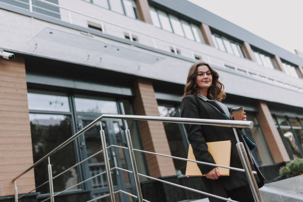 istock Gladsome office worker walking from the building and smiling 1241163018