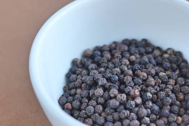 istock Black pepper in the white bowl on brown background 1241165737