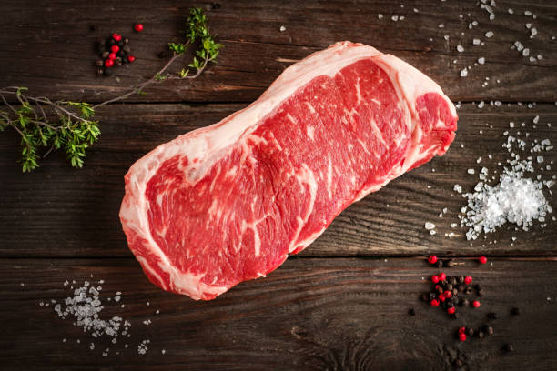 striscia cruda loin bistecca su sfondo bianco in legno in stile rustico - strip steak immagine foto e immagini stock