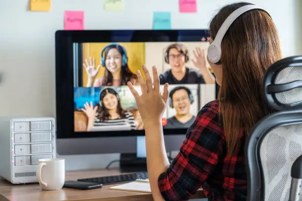 Photo of Rear View of Asian Business woman say hello with teamwork colleague in video conference