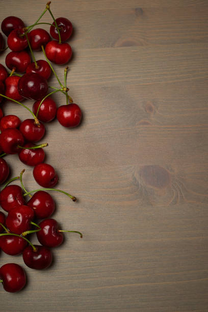 istock Green spring red cherries on wooden background selective focus cherry 1241194450