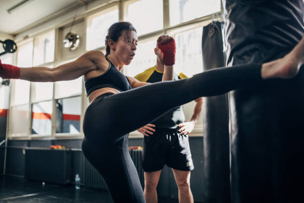 istock Kick box instructor looking how woman is kicking punching bag 1241200856