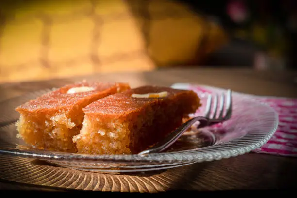 Photo of Turkish Dessert sambali, sambaba or sam tatlisi served in a plate with fork and knife on brown table.