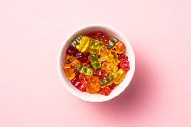 Gummy bears, jelly candy in bowl. Colorful bonbons on colorful background. Top view.
