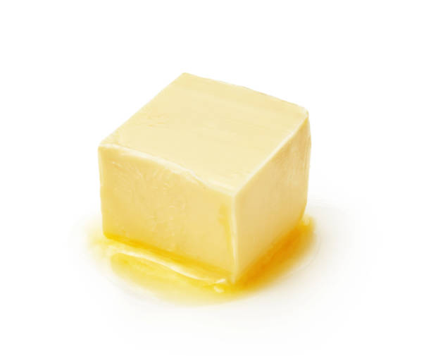 A piece of melting butter isolated on white background. Butter cube. stock photo