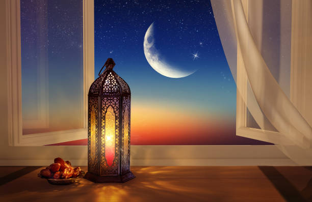Ramadan lantern by the open window. Beautiful Greeting Card with copy space for Ramadan and Muslim Holidays. An illuminated Arabic lamp. Mixed media. stock photo