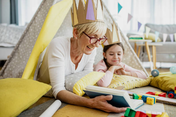 a grandmother is reading a book to the granddaughter - grandparent reading grandmother child imagens e fotografias de stock