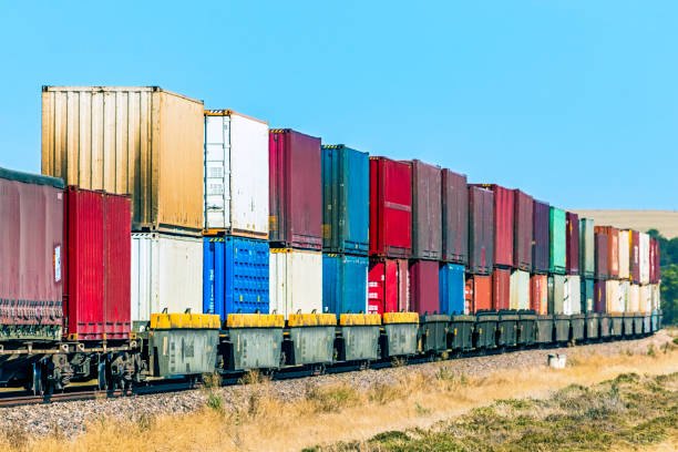 Colourful container freight train delivering merchandise to distribution warehouse A colourful double stack container freight train carrying the equivalent load of dozens of big trucks (lorries) is transporting valuable merchandise to a distribution warehouse at its interstate destination. All logos and ID removed. stackable stock pictures, royalty-free photos & images