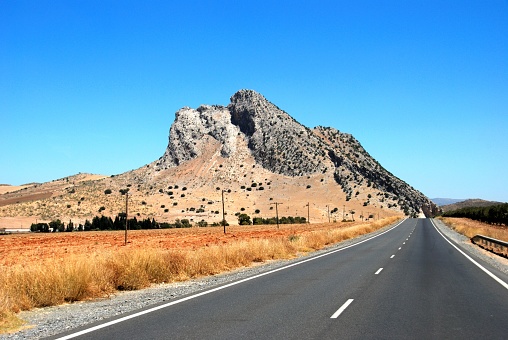 View along a straight road towards the lovers rock (La Pena de los Enamoradas), Antequera, Malaga Province, Andalucia, Spain.