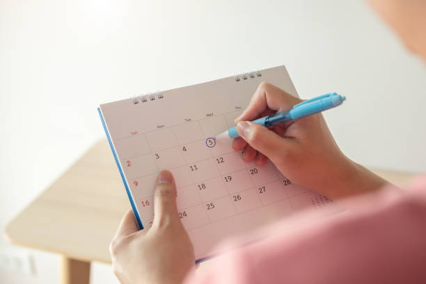 istock Hand with pen mark at 5th on calendar date with blue circle 1241287616