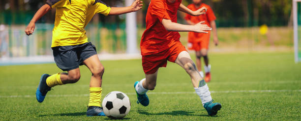 sporty football boys running after ball in duel. school soccer competition between two junior level players. multi-ethnic kids play sports - soccer ball youth soccer event soccer imagens e fotografias de stock