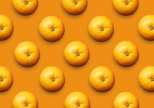 A group of juicy oranges, tangerines or clementines isolated on orange colored background. View from above. Modern design. Set of tropical citrus fruits pattern.