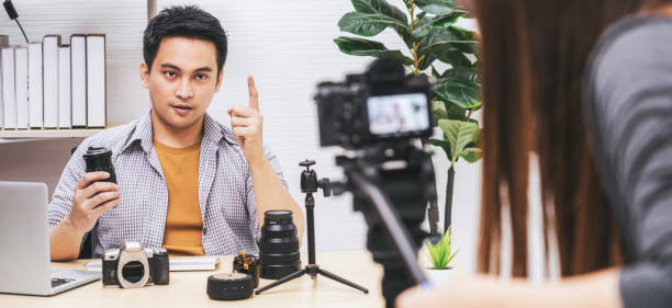 banner kamera, die video und live mit laptop des asiatischen vlogger mann zufrieden das kameraobjektiv jedes medium, teilen von wissen an das publikum über kamera über social-media-kanal, vlog und influencer-konzept - camera lens home video camera broadcasting stock-fotos und bilder