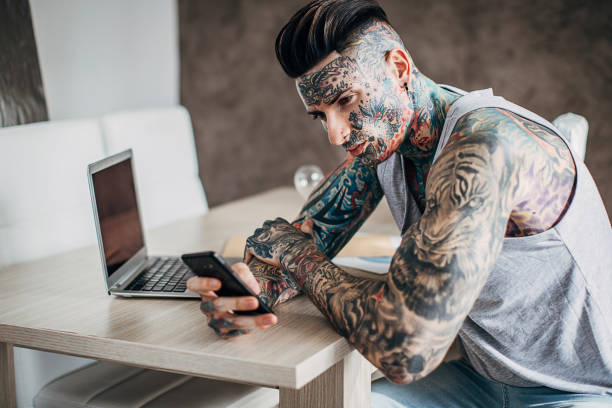 istock Man with whole body covered in tattoos using smart phone at home 1241337822