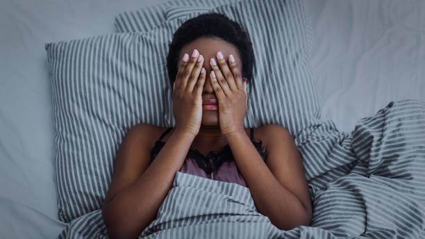 African american girl closed eyes with hands in bed Insomnia and pain. African american girl closed eyes with hands in bed, dark insomnia photos stock pictures, royalty-free photos & images