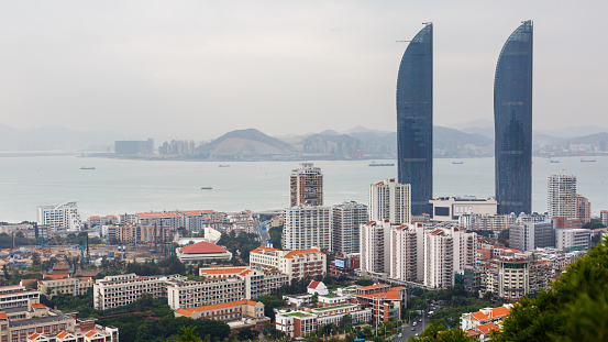 Xiamen, Fujian Province / China - Dec 5, 2015: Cityscape of Xiamen with Shimao Straits Towers. In the background the South China Sea.