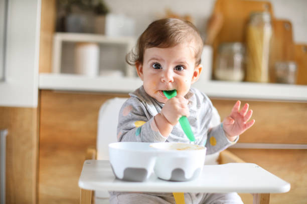 istock Baby eating by herself in high chair 1241357076