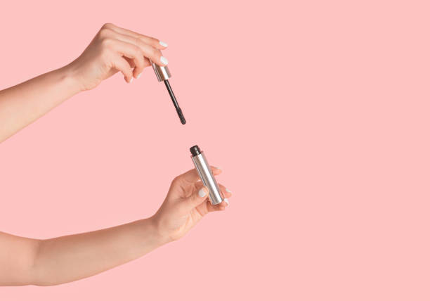 istock Female hands showing mascara on pink background, closeup. Space for text 1241358164