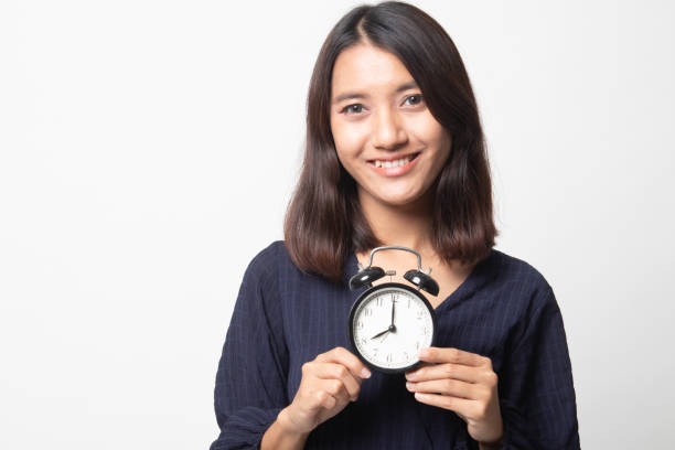 istock Young Asian woman smile with a clock. 1241361964
