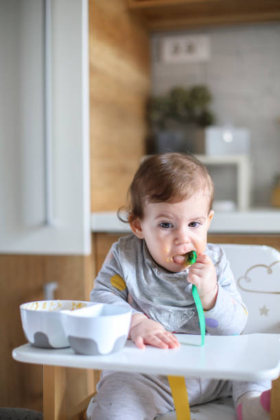 istock Baby eating by herself in high chair 1241364182