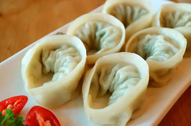 Photo of Closeup a Plate of Steamed Mandu or Korean Dumplings Served on Wooden Table