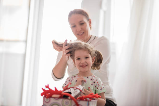 Girl smiling when having her pigtail hairstyle done Happy woman getting hr daughter's hair tidy human hair women brushing beauty stock pictures, royalty-free photos & images