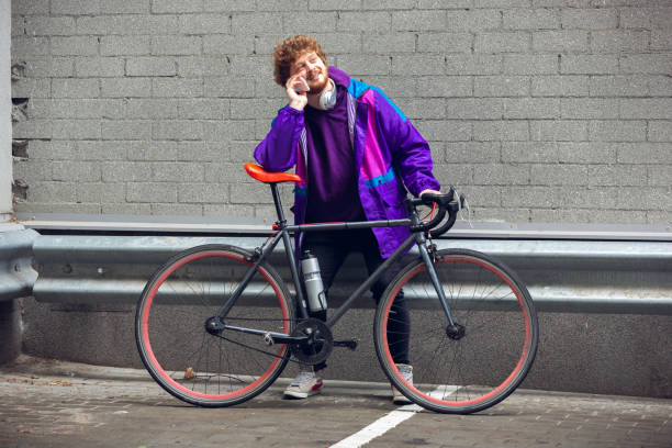 istock Handsome young man using mobile phone and headphones while standing near his bicycle beside him 1241408687