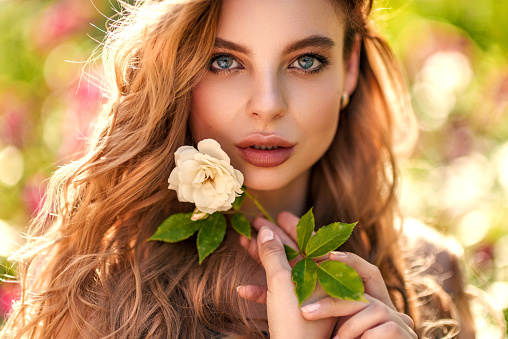 beautiful photo girl in the warm rays of the soft sun in spring with roses. makeup and hairstyle concept.