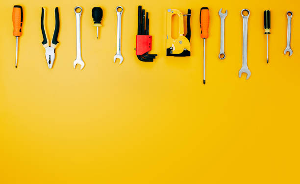 istock Tools top view on yellow background. Plier, open wrenches, screwdrivers and staple gun flat lay with copy space. 1241430032