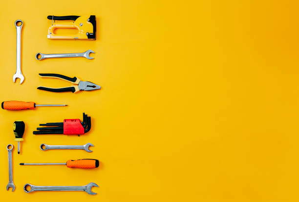 istock Tools top view on yellow background. Plier, open wrenches, screwdrivers and staple gun flat lay with copy space. 1241430054