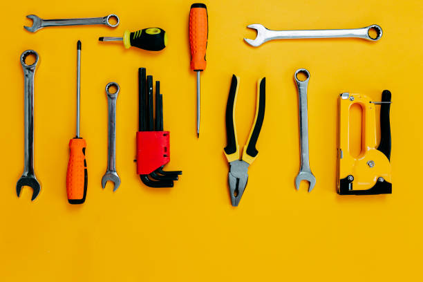 istock Tools top view on yellow background. Plier, open wrenches, screwdrivers and staple gun flat lay with copy space. 1241430444