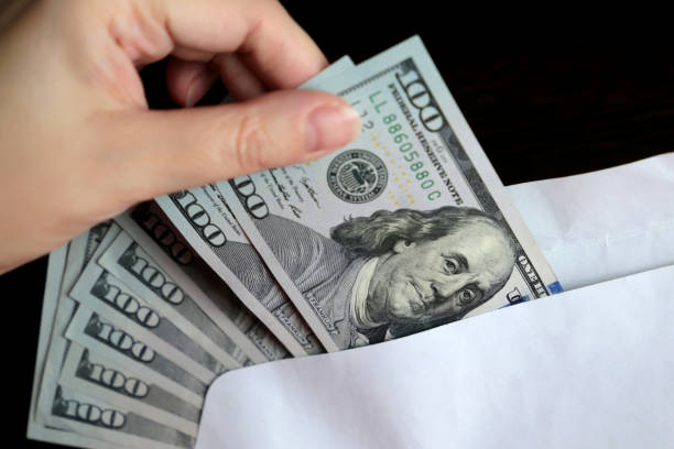 istock Envelope with US dollars in female hands 1241432318