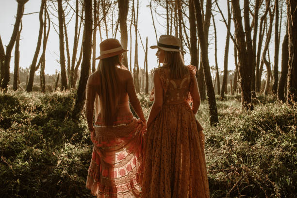 Rear view of two young women walking in a forest at sunset